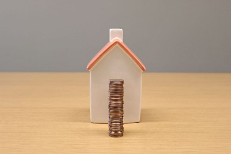 a miniature home and a stack of coins