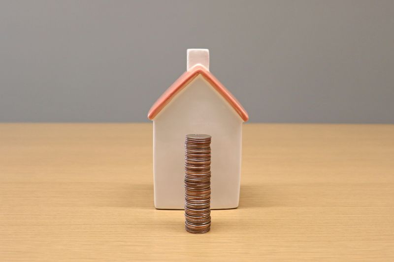 a miniature home and a stack of coins